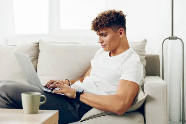 男人室内网络空间笔记本电脑现代T恤衫自由职业看互联网交流坐着聊天高加索白色电脑快乐浏览的人 — 图库照片