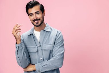 Sakallı şık esmer adam pembe bir arka planda beyaz tişört ve kot pantolonla kameraya bakıyor ve yüzünde neşeli bir gülümseme, kopyalama alanı. Yüksek kalite fotoğraf