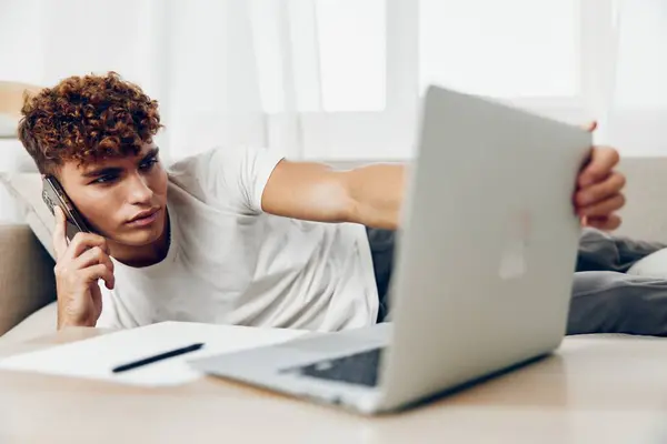 男子室内幸福生活现代使用短信互联网手机智能手机学生沙发微笑通信移动博客手持在线笔记本电脑 — 图库照片