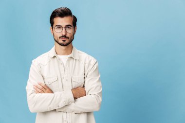 Miyopluk ve hipermetrop için gözlük takan şık bir adamın portresi, beyaz tişörtlü mavi bir arka plan, modaya uygun giyim tarzı, uzay boşluğu. Yüksek kalite fotoğraf