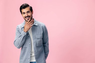 Sakallı, zarif esmer bir adamın portresi. Beyaz tişörtlü, kot pantolonlu güzel bir arka planda güzel bir gülümseme. Yüzünde neşe dolu bir gülümseme. Yüksek kalite fotoğraf