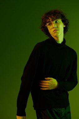 Gözlüklü adam portresi moda ve tarz duygusu, yeniyetme ergen yaşam tarzı, yeşil arka plan karışık neon ışığı, fotokopi alanı. Yüksek kalite fotoğraf