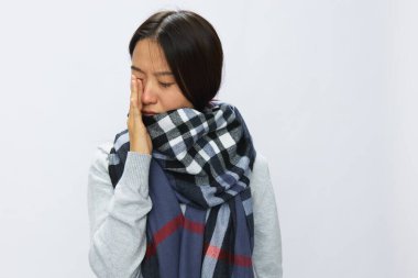 Asyalı kadın soğuk algınlığı nedeniyle baş ağrısı ve diş ağrısından elini kaldırdı. Beyaz arka planda kareli eşarp takılı kovid 19 virüsü, kopyalama alanı. Yüksek kalite fotoğraf