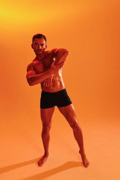 Man bodybuilder boxer muscle workout with naked torso with abs posing in studio. Advertising, sports, active lifestyle, colored yellow light, competition, challenge concept. . High quality photo