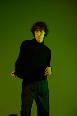 Gözlüklü adam portresi moda ve tarz duygusu, yeniyetme ergen yaşam tarzı, yeşil arka plan karışık neon ışığı, fotokopi alanı. Yüksek kalite fotoğraf