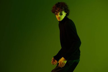 Gözlüklü erkek dansçı moda ve tarz duygu modeli dans, hipster gençlik yaşam tarzı, portre yeşil arka plan karışık neon ışığı, fotokopi alanı. Yüksek kalite fotoğraf