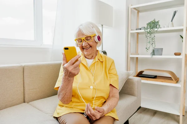 Happy elderly woman looking into phone video call smile, technology for communication, bright modern interior, lifestyle online communication. High quality photo