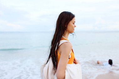 Sırt çantalı genç bir kadın sahilde yürüyor, yaz tatili Bali 'de okyanus kıyısındaki bir adada. Yüksek kalite fotoğraf
