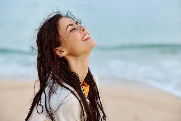 Portrait of a woman smile with teeth in a yellow tank top and white beach shirt with wet hair after swimming on the ocean beach sunset light. High quality photo