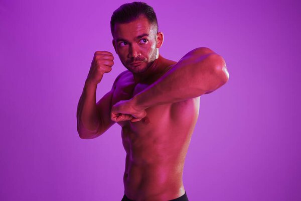 Man bodybuilder boxer muscle workout with naked torso. Advertising, sports, active lifestyle, colored purple light, competition, challenge concept. . High quality photo