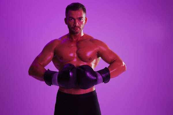 Man bodybuilder boxer muscle workout with naked torso. Advertising, sports, active lifestyle, colored purple light, competition, challenge concept. . High quality photo
