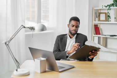 İnternet adamı gülümseyen ofis içi bilgisayar eğitim masasında oturan Afrikalı web şirketinin serbest çalışan iş yerinde Amerikalı programcı öğrenci yönetici dizüstü bilgisayarını kullanıyor.