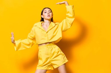 Model kız dans eder, mutlu, şık, modaya uygun, neşeli, beyaz arka plan, izole, sarı, oldukça çekici, eğlenceli, genç, güzel, moda.