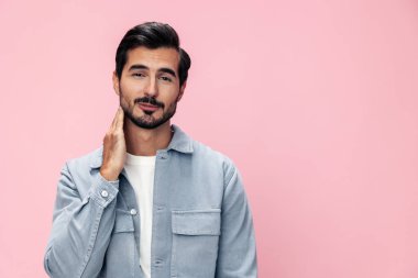 Beyaz tişörtlü, pembe arka planda sakallı, esmer bir adamın moda portresi. Yüzünde gülücük ve neşe dolu bir duygu var. Yüksek kalite fotoğraf