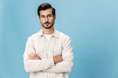 Miyopluk ve hipermetrop için gözlük takan şık bir adamın portresi, beyaz tişörtlü mavi bir arka plan, modaya uygun giyim tarzı, uzay boşluğu. Yüksek kalite fotoğraf