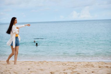 Spor kadın plaj boyunca sarı bir atlet ve kot şortla kumsalda koşuyor. Uçan saçlar, deniz manzarası, plaj tatili ve seyahat. Yüksek kalite fotoğraf