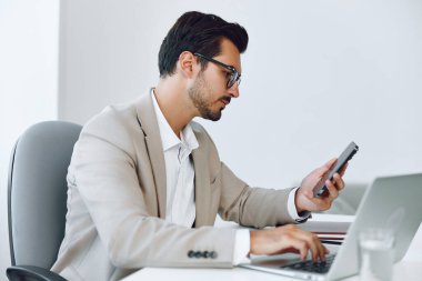 Çekici adam oturan bilgisayar işadamı iş yeri bilgisayarı bağlantısı üzerinde çalışıyor başarılı bir konuşma belgesi üzerinde çalışıyor mutlu erkek telefon beyaz ofis gülümsemesi