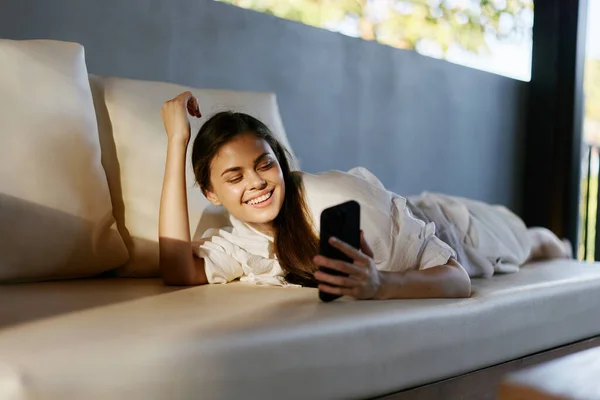 女人的短信回家看成年人的智能手机沙发放松迷人的生活方式移动沙发智能房间美女手机技术女士在线 — 图库照片