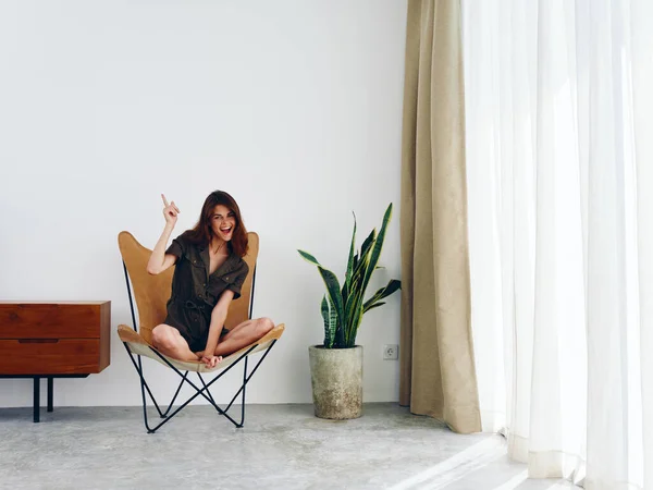 女人坐在靠窗的皮革扶手椅上笑着 时髦的斯堪的纳维亚内部生活方式 复制空间 高质量的照片 — 图库照片