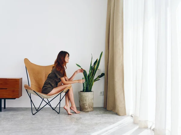 Woman sitting on a chair near the window smiling, modern stylish interior Scandinavian lifestyle, copy space. High quality photo