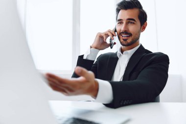 Ofis işadamı masasında oturuyor ve dizüstü bilgisayarda çalışıyor ve telefonla konuşuyor, modern takım elbise, finans ve başlangıç konsepti ve veri analizi, parlak bir ofiste çalışma tarzı. Yüksek kalite fotoğraf