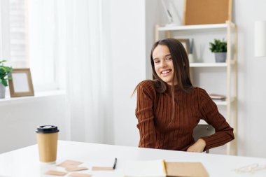 Yuvadaki genç kız masasında mutlu bir şekilde bilgisayar öğrencisi olarak oturuyor. Not defteri sınavı hazırlığı online çocukluk eğitimi öğrencisi beyaz beyaz beyaz beyaz masa ödevi.