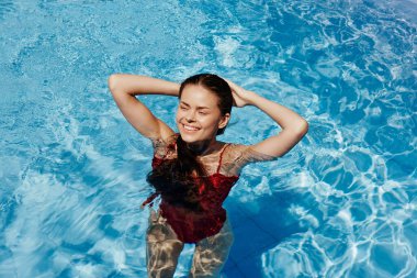 Kırmızı mayo içinde yüzen, uzun saçlı, güneş kremli cilt koruması olan, tatilde rahatlama konsepti olan mutlu bir kadın. Yüksek kalite fotoğraf