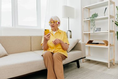 Mutlu, yaşlı bir kadın telefon görüşmeleri gülümsemesini, iletişim teknolojisini, parlak modern iç mekanı, çevrimiçi yaşam tarzını araştırıyor. Yüksek kalite fotoğraf