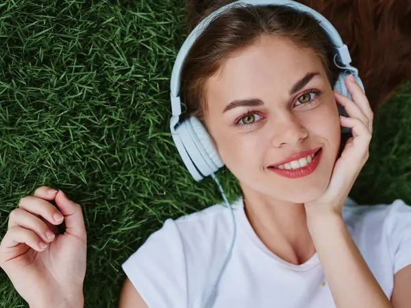 Genç Kız Kulaklıkla Müzik Dinliyor Parktaki Yeşil Çimlerde Yatıyor Beyaz — Stok fotoğraf