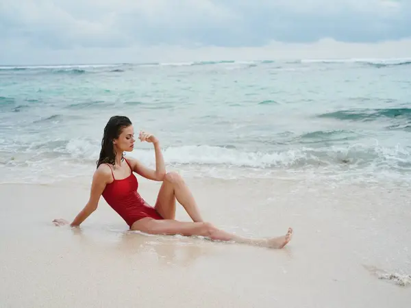 Una Donna Costume Bagno Rosso Siede Sulla Sabbia Riva Mare — Foto Stock