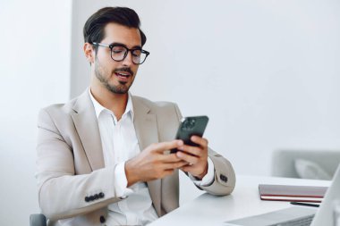 Gülümseyen adam ofisi modern mutlu mobil masa bağlantısı çekici iş adamı laptop belgesi bilgisayar telefon sahibi yetişkin kablosuz yönetici girişimciyi ara