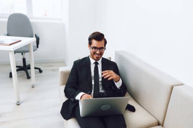 İnternet adamı Kafkasyalı görünümlü kanepe teknolojisi iş gözlükleri telefon odası, daire yakışıklı kanepe çevrimiçi erkek rahat dizüstü bilgisayar gülen ev