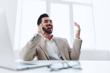 Ofis işadamı masasında oturuyor ve dizüstü bilgisayarda çalışıyor ve telefonla konuşuyor, modern takım elbise, finans ve başlangıç konsepti ve veri analizi, parlak bir ofiste çalışma tarzı. Yüksek kalite fotoğraf