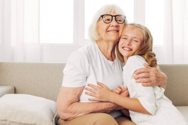 Torun kadın yaşam tarzı, aile hayatı, aile kucaklaşması, kız evlat, anne, kanepe, çocuk, kanepe, mutlu torun, yaşlı yaşlı kız, büyükanne.