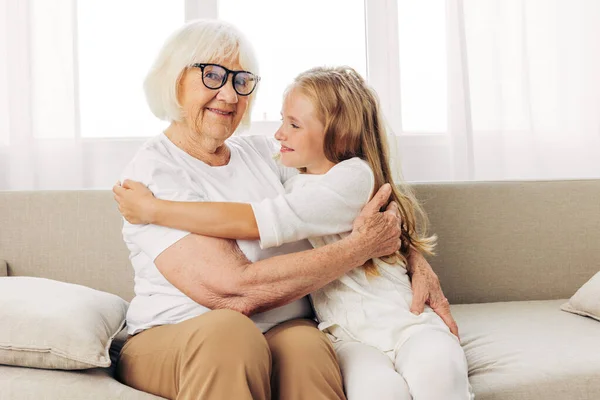 Couch woman sofa child family daughter elderly love lifestyle sitting grandmother senior hug girl home mother happy granddaughter old generation