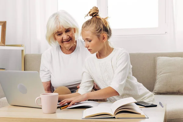 Family grandmother copy space two white granddaughter child education laptop indoors selfie bonding people hugging video togetherness smiling call sofa t-shirt photography