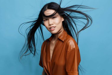 Arkaplanda güzel bir Asyalı kadın portresi uzun saçlı neşeli moda stüdyosu mutlu moda kızı çekici kız gülümseyen Japon mavi Koreli kendine güvenen sevimli