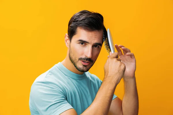 Man looking smiling lifestyle hairbrush face yellow brushing haircut close-up loss hair holding portrait beard comb background barber hair handsome background hairstyle studio care combing beauty