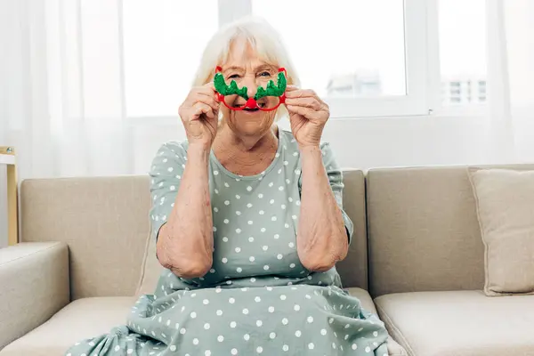 Woman year elderly smile xmas mature holiday caucasian female pensioner portrait new grandmother home christmas glasses couch happy year cozy adult happiness