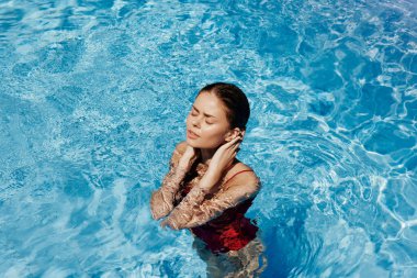 Havuzda yüzen kırmızı mayo, güneş ışığında uzun saçlar, güneş kremli cilt koruması, tatilde dinlenme konsepti. Yüksek kalite fotoğraf