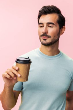 Erkek model kahveden pembe izole edilmiş enerji arka planına çay fincanı öğrenci tişörtü stüdyosu fotokopisi, uykusuzluk moda hipster sıcak kağıt kupa uyku gülümsemesi iç.