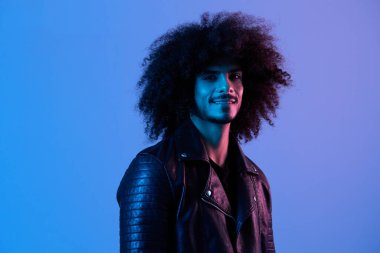 Mavi arka planda kıvırcık saçlı, çok uluslu, açık renkli siyah deri ceketli moda adamı portresi, modern konsept. Yüksek kalite fotoğraf