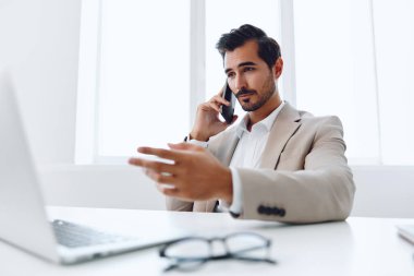 Ofis işadamı masasında oturuyor ve dizüstü bilgisayarda çalışıyor ve telefonla konuşuyor, modern takım elbise, finans ve başlangıç konsepti ve veri analizi, parlak bir ofiste çalışma tarzı. Yüksek kalite fotoğraf