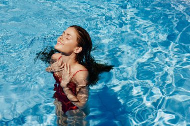 Havuzda yüzen kırmızı mayo, güneş ışığında uzun saçlar, güneş kremli cilt koruması, tatilde dinlenme konsepti. Yüksek kalite fotoğraf