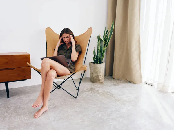 Evde dizüstü bilgisayarlı bir sandalyede oturan kadın mutsuzluk bıkkınlık, modern stil İskandinav yaşam tarzı, kopyalama alanı. Yüksek kalite fotoğraf