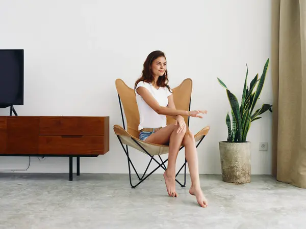 坐在皮革扶手椅上的女人笑着带着牙齿生活方式 悠闲地呆在家里 用白色的墙壁装饰着时髦的现代室内装饰 复制空间 高质量的照片 — 图库照片