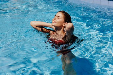 Kırmızı mayo içinde yüzen mutlu bir kadın, güneş ışığında uzun saçlar, güneş kremi ile cilt koruması, tropikal iklimde tatilde dinlenme kavramı. Yüksek kalite fotoğraf