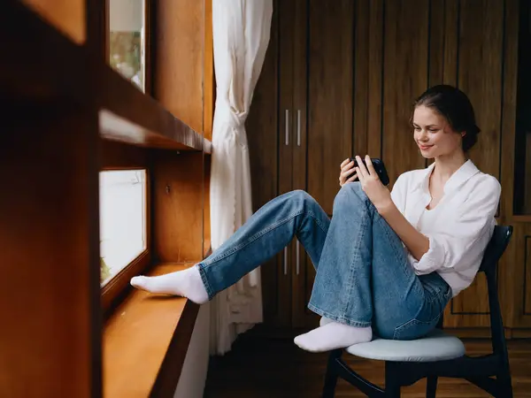 Young Woman Sitting Window Phone Hand Smile Looking Online Spring — Stock Photo, Image