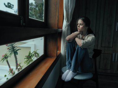 Kadın depresyona girer ve pencerenin kenarında oturur ve doğaya bakar, yağmurlu hava ve hayal kırıklığı, ev hayatı tarzı, yalnızlık. Yüksek kalite fotoğraf