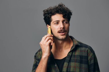 Sıradan bir adam stüdyosu ayakta duran bir saç telefonu beyaz bir yetişkin arka planı genç bir gömlek gri, yakın plan insan yaşam tarzı güzel teknoloji insan mutlu stil pozitif dinleyin